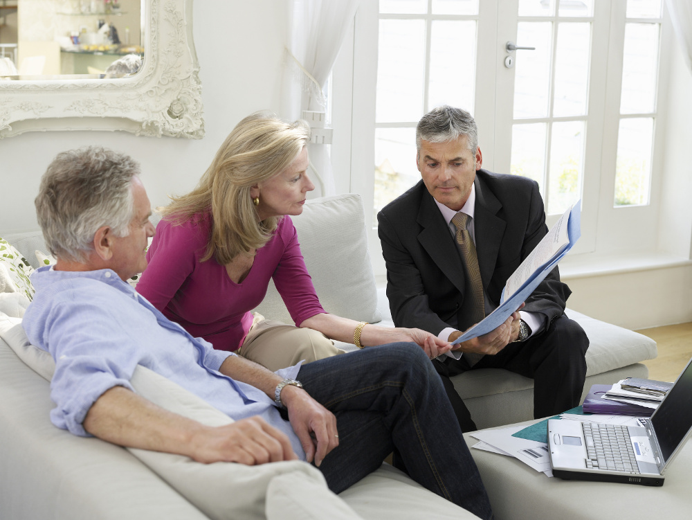 Mature couple sitting on sofa with financial advisor