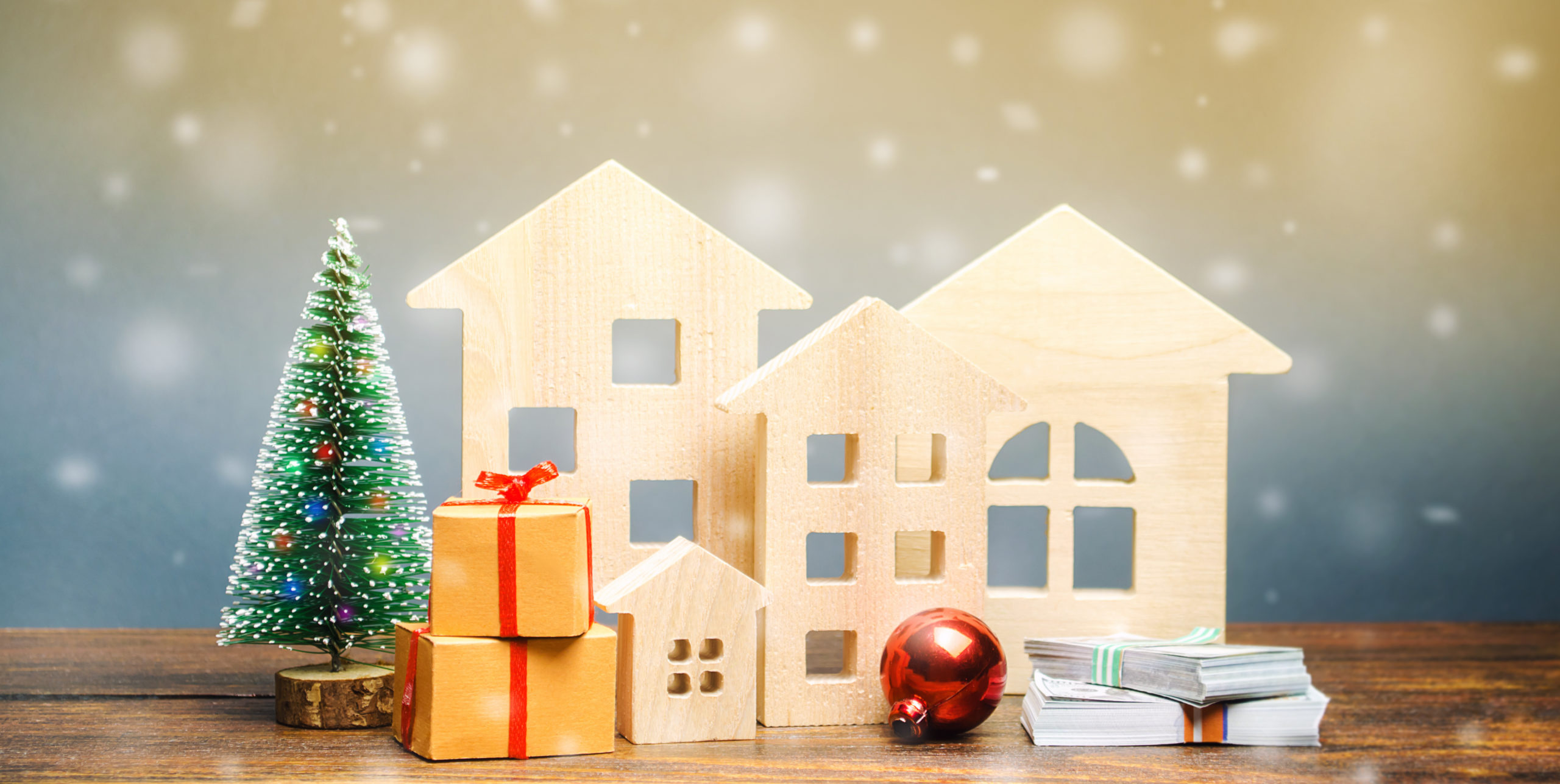 Wooden houses, Christmas tree, money and gifts. Christmas Sale of Real Estate. New Year discounts for buying housing. Purchase apartments at a low price. Holiday discounts. Favorable prices